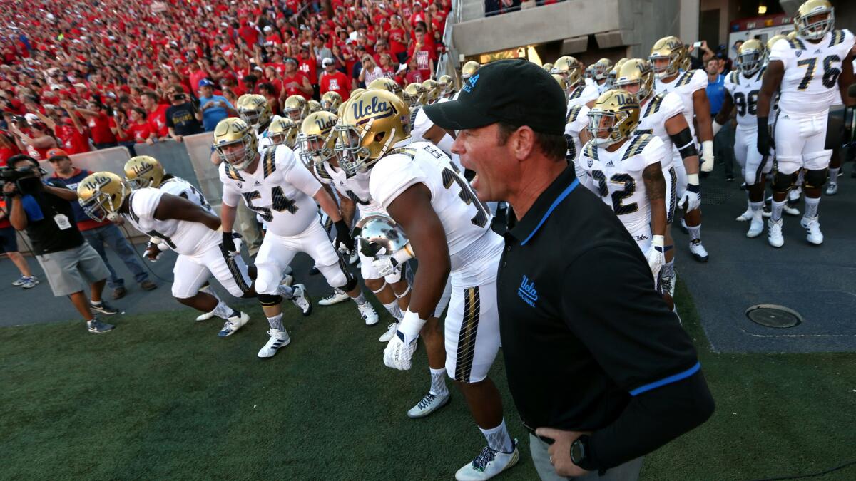 Coach Jim Mora, who has fostered a chip-on-the-shoulder mentality during his UCLA tenure, leads the Bruins onto the field to play Arizona on Sept. 26.