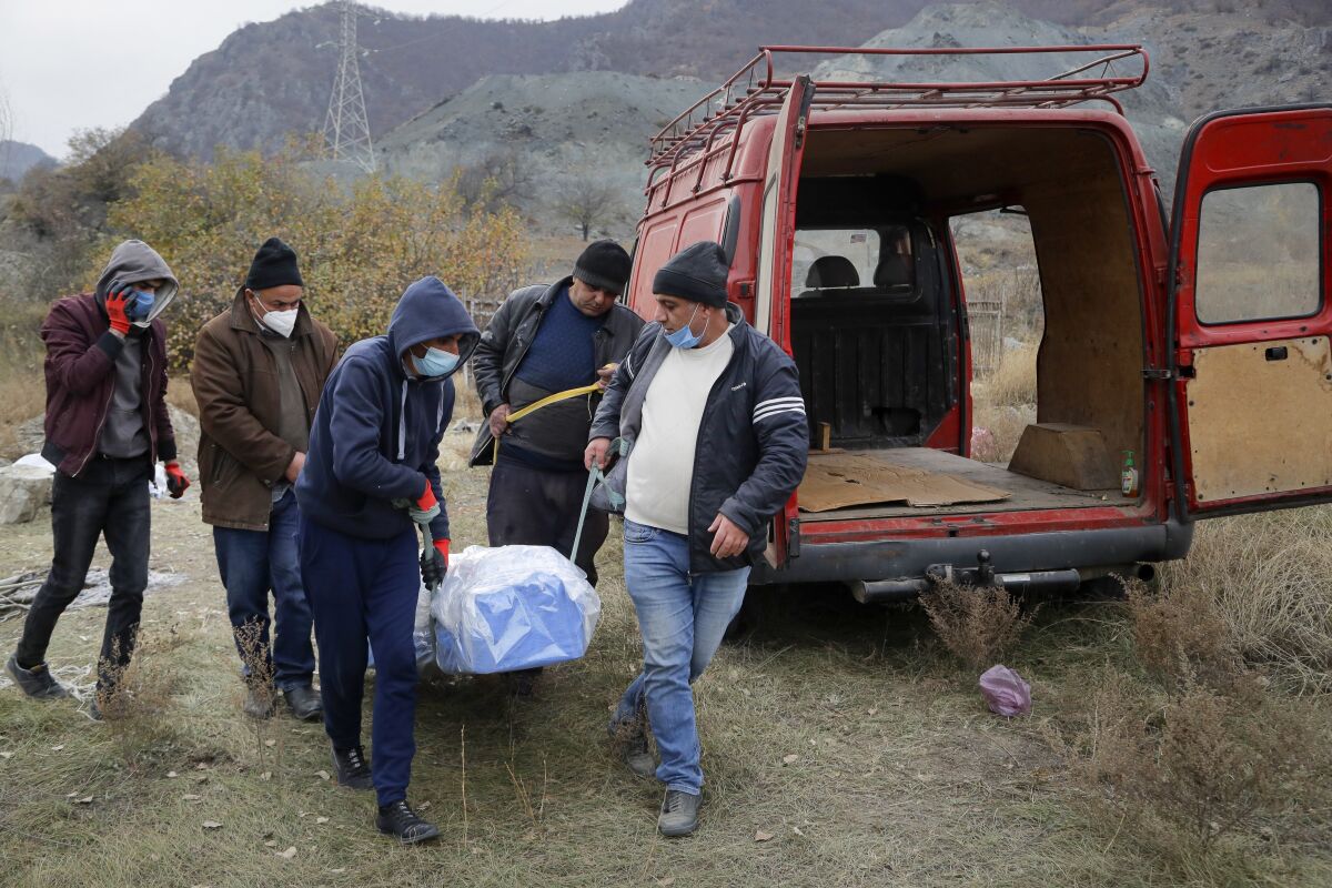 Ethnic Armenians carry a coffin with the body of their relative Sergei Gabrilyan, moved from a grave, to repatriate his remains to Armenia, in Kalbajar in separatist region of Nagorno-Karabakh, Monday, Nov. 16, 2020. It is unclear when any civilians might try to settle in Karvachar, which will now be known by its Azeri name Kalbajar, or elsewhere. Armenians who are going to leave separatist region of Nagorno-Karabakh dig up the remains of their ancestors to bring them from the territory, which is to be handed over to Azerbaijanis. (AP Photo/Sergei Grits)