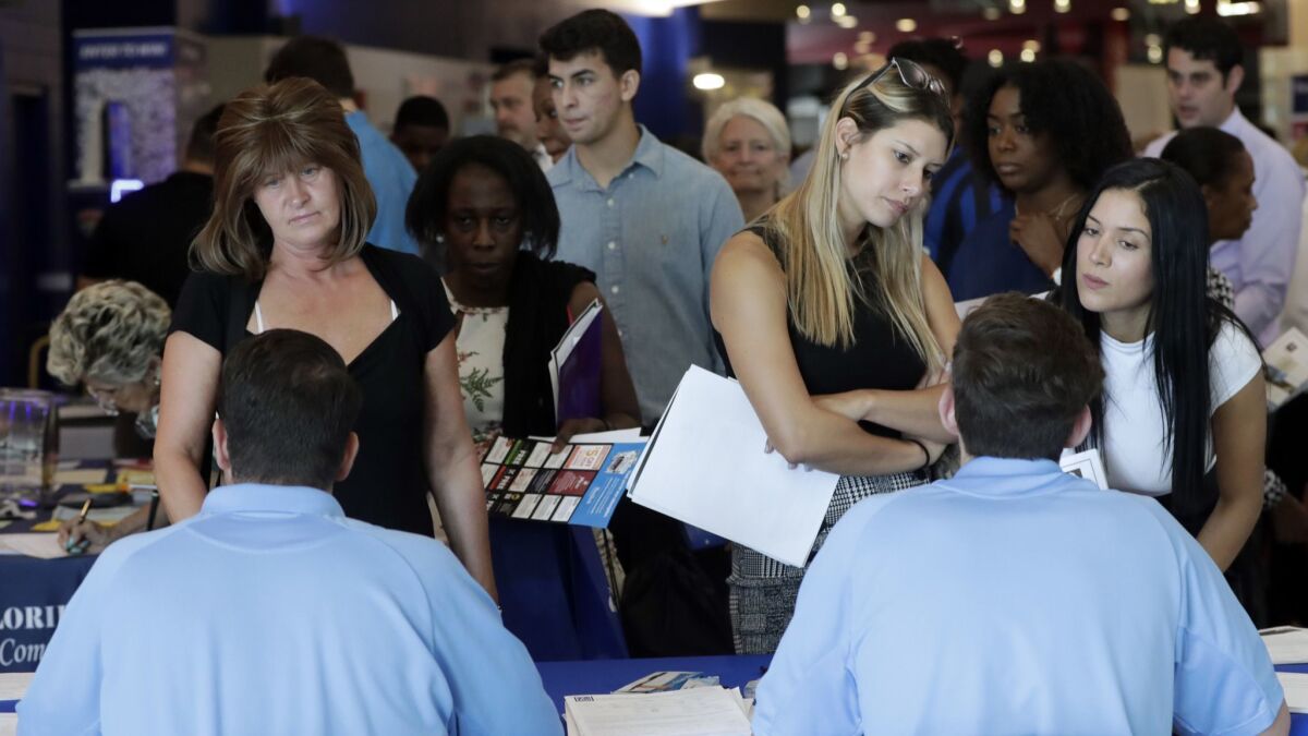 Job applicants talk with representatives from Aldi at a job fair in Florida in June.