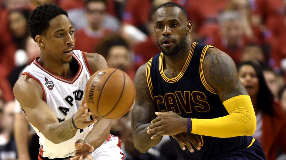 Raptors guard DeMar DeRozan flips a pass to a teammate after driving past Cavaliers forward LeBron James during the second half of Game 3 on Saturday.