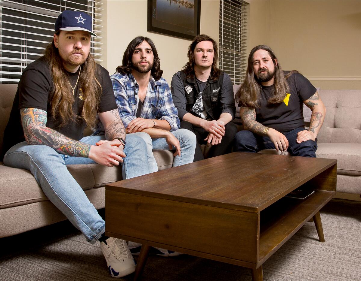 Power Trip band members sit on a couch as they pose for a photo.
