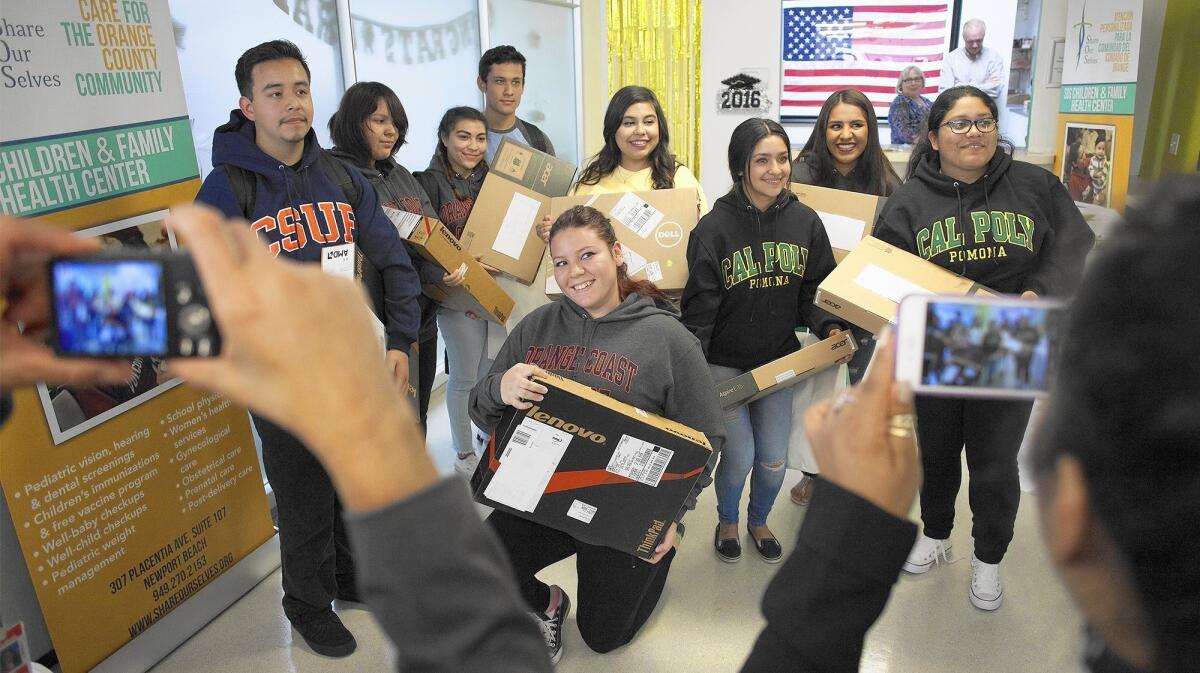 Estancia High School seniors gather for a group photo after receiving free laptops during a Share Our Selves high school senior project ceremony.