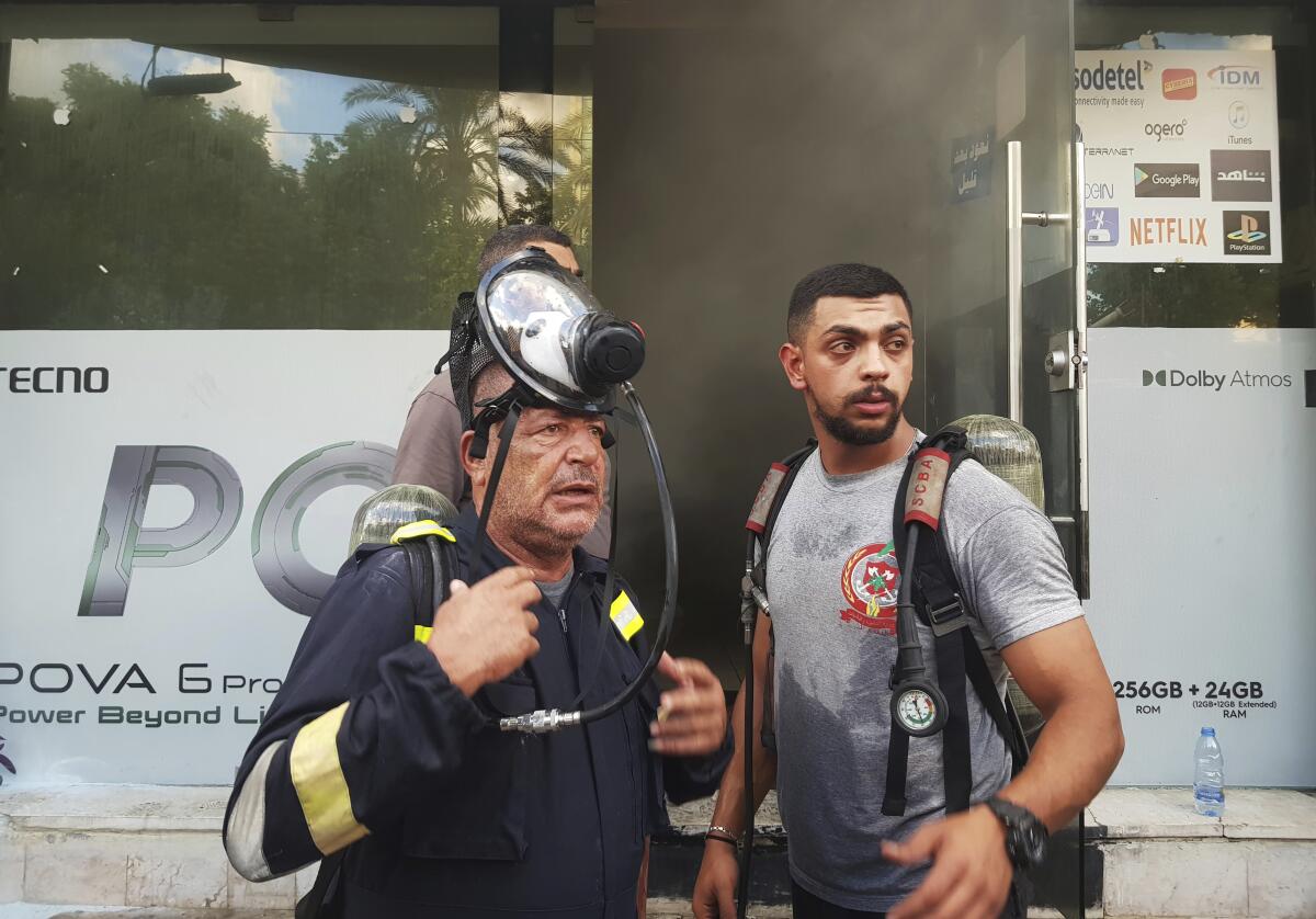 Firefighters stand outside a damaged store