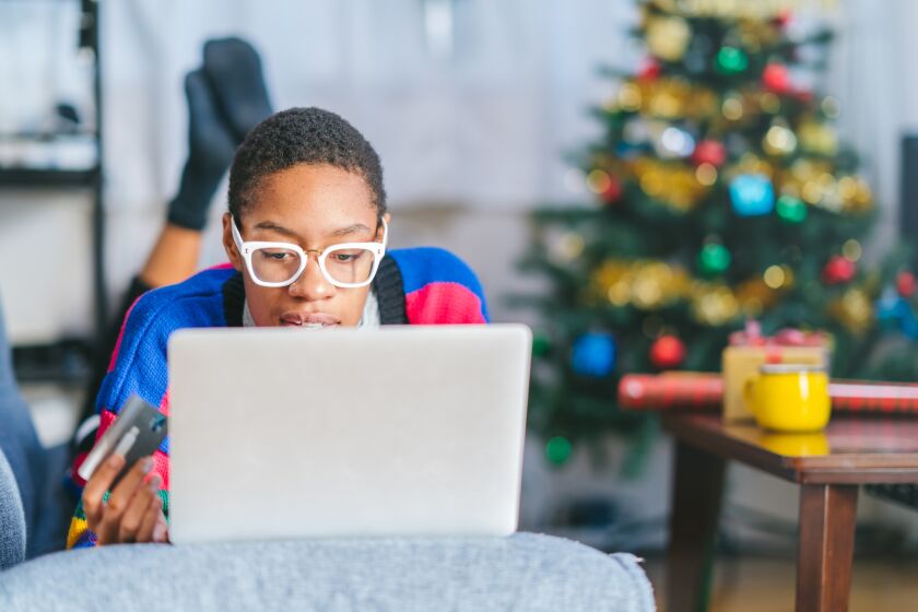 A young black African American woman is shopping online at home at Christmas.