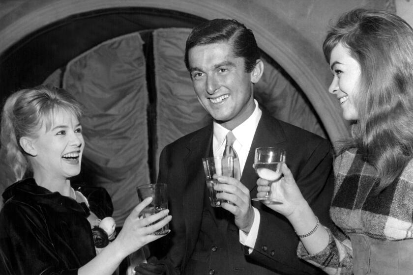 Robert Evans, center, with Sophie Daumier, left, And Marie Versini at a coctial party at a Paris restaurant on December 3. 1959.