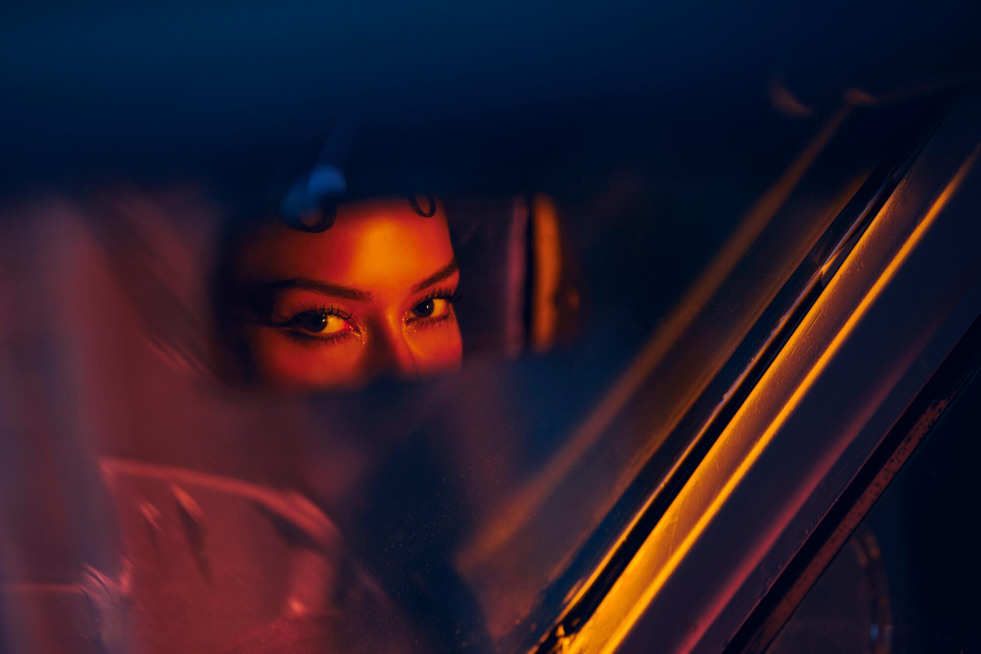 A photo of a person's eyes looking into the car's rearview mirror.