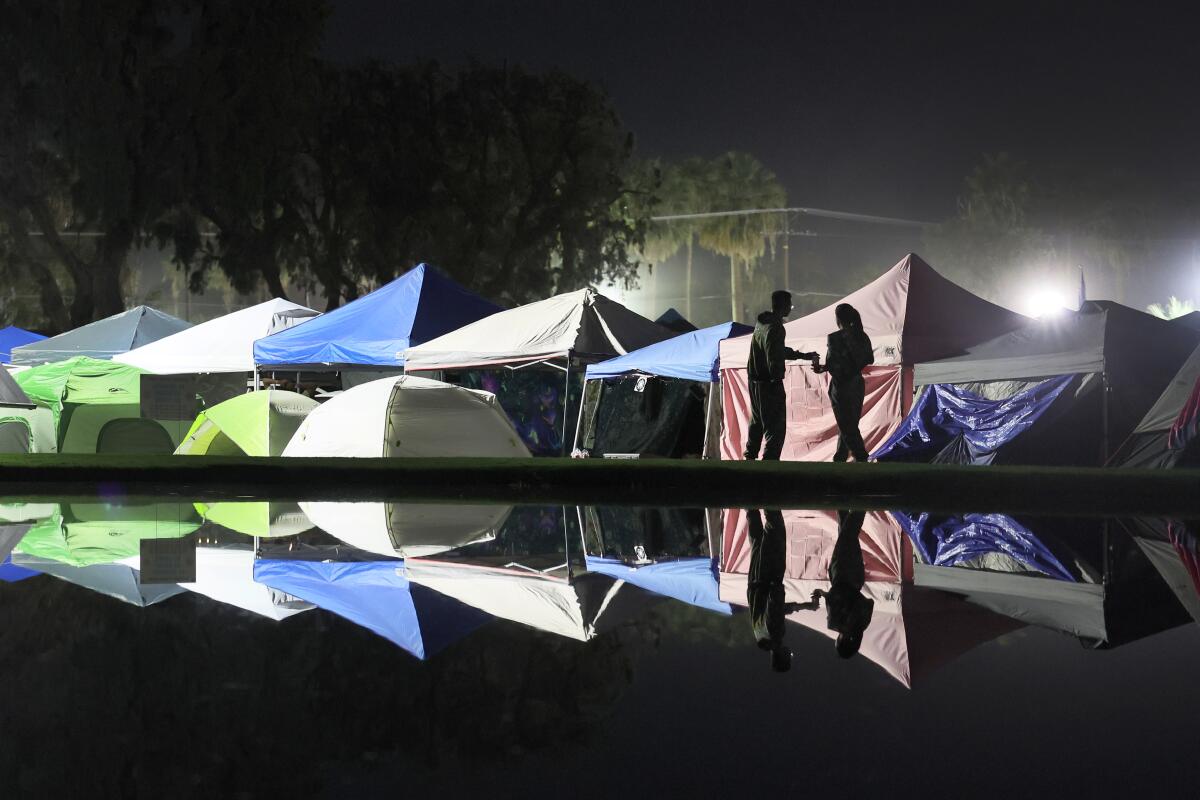 Campers and canopies are reflected successful the water arsenic they caput backmost to their campground astatine Coachella.