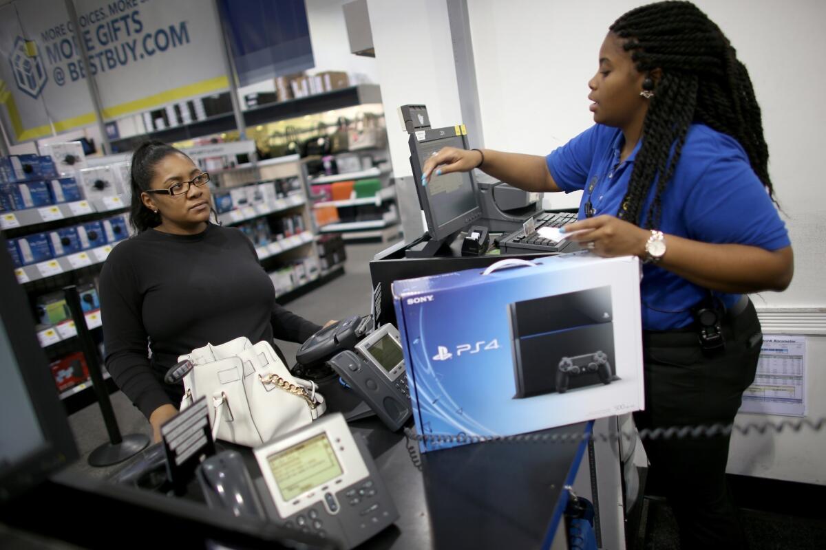 Kimberly Lee, left, purchases a Sony Playstation 4 from Ashley Delva, a sales associate at Best Buy in in Pembroke Pines, Fla.
