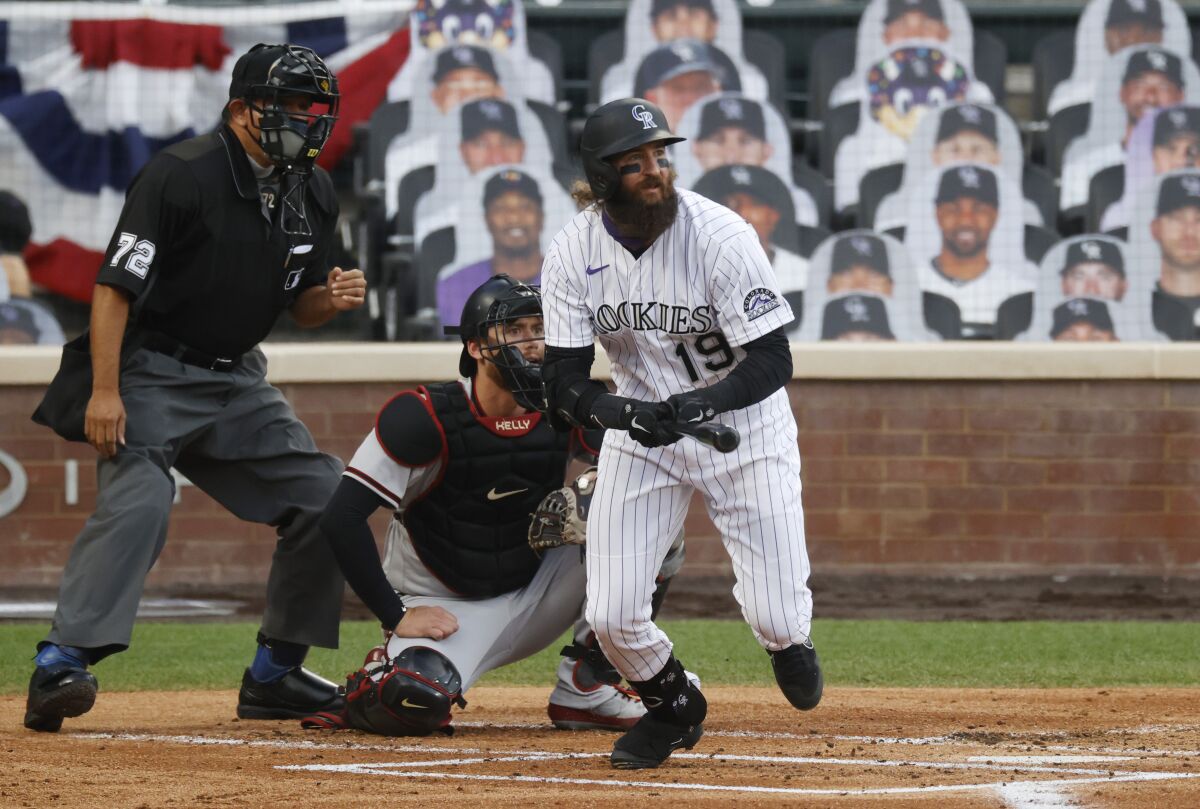 Colorado Rockies' Charlie Blackmon, front, follows the flight of his single as he breaks from the batter's box as Arizona Diamondbacks catcher Carson Kelly, back right, and home plate umpire Alfonso Marquez look on in the first inning of a baseball game Tuesday, Aug. 11, 2020, in Denver. (AP Photo/David Zalubowski)