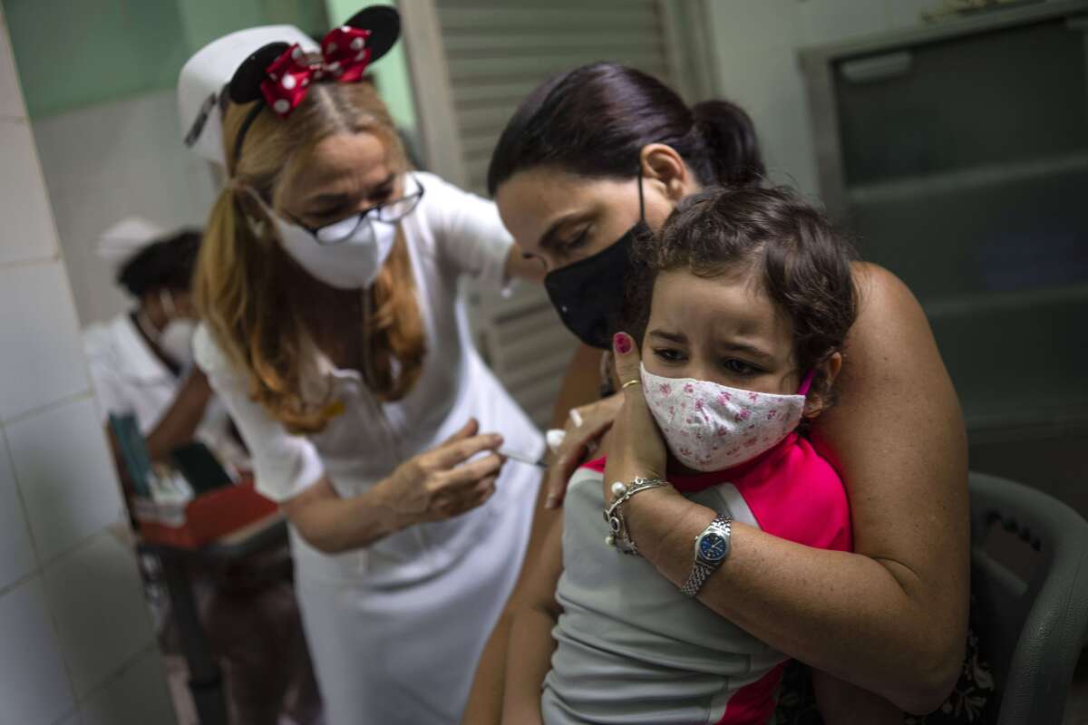 A mother holds her daughter who is injected with a dose of the Soberana-02 COVID-19 vaccine, in Havana, Cuba, Thursday, Sept. 16, 2021. Cuba began inoculating children as young as 2-years-old with locally developed vaccines on Thursday.(AP Photo/Ramon Espinosa)