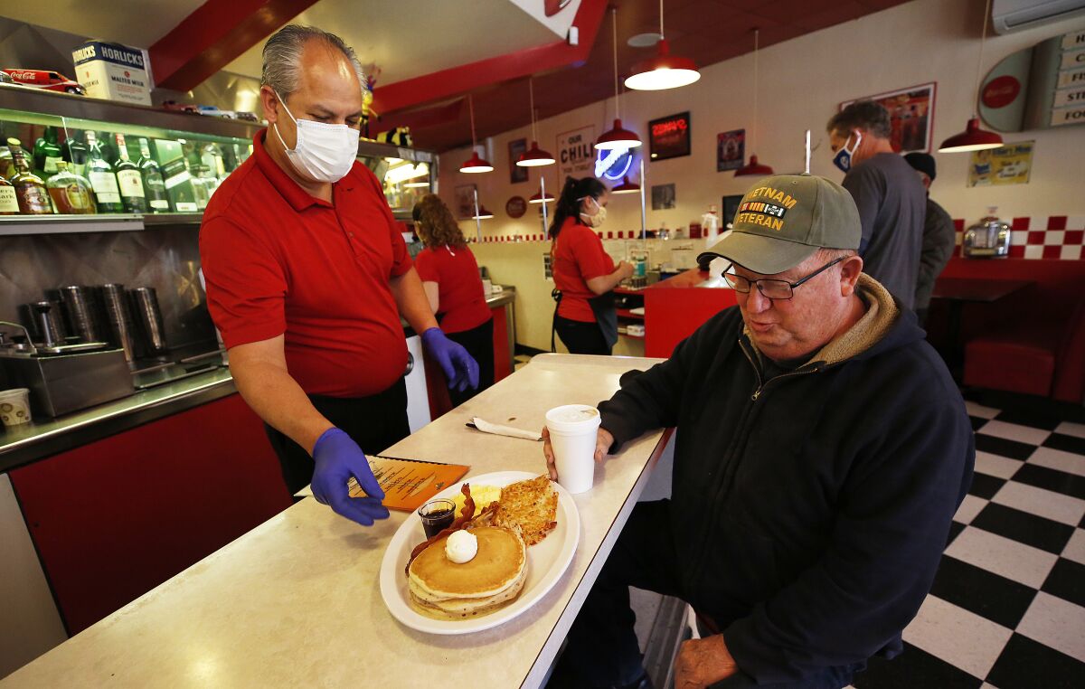 Busy Bee Cafe owner Raymundo Sanchez serves breakfast to Cal Youngblood, 75, at the downtown Ventura restaurant on May 21.
