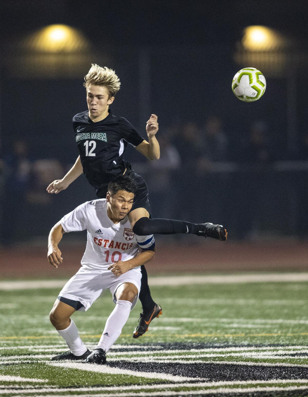 Costa Mesa's Jackson Galitski lands on top of Estancia's Marcos Arreola while going for the ball during an Orange Coast League match on Wednesday.
