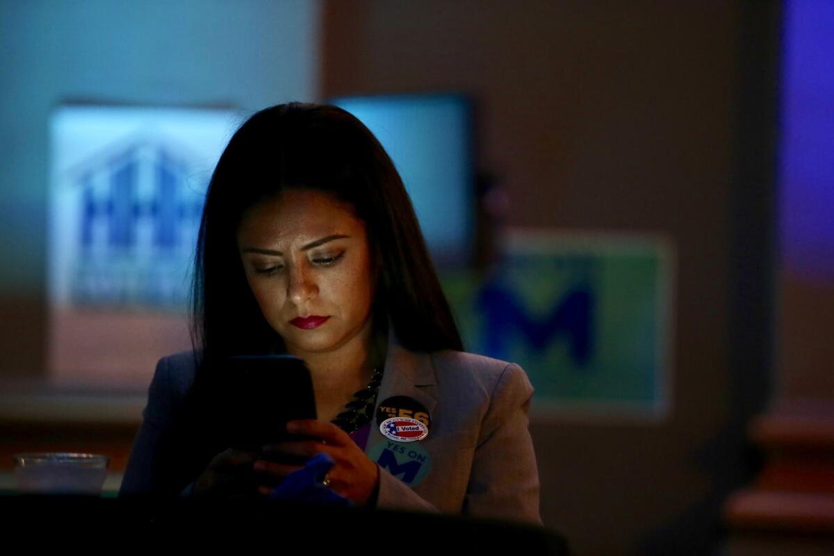 Claudia Goytia checks her smartphone for any good news regarding Hillary Clinton while attending a party for a local measure in downtown Los Angeles.