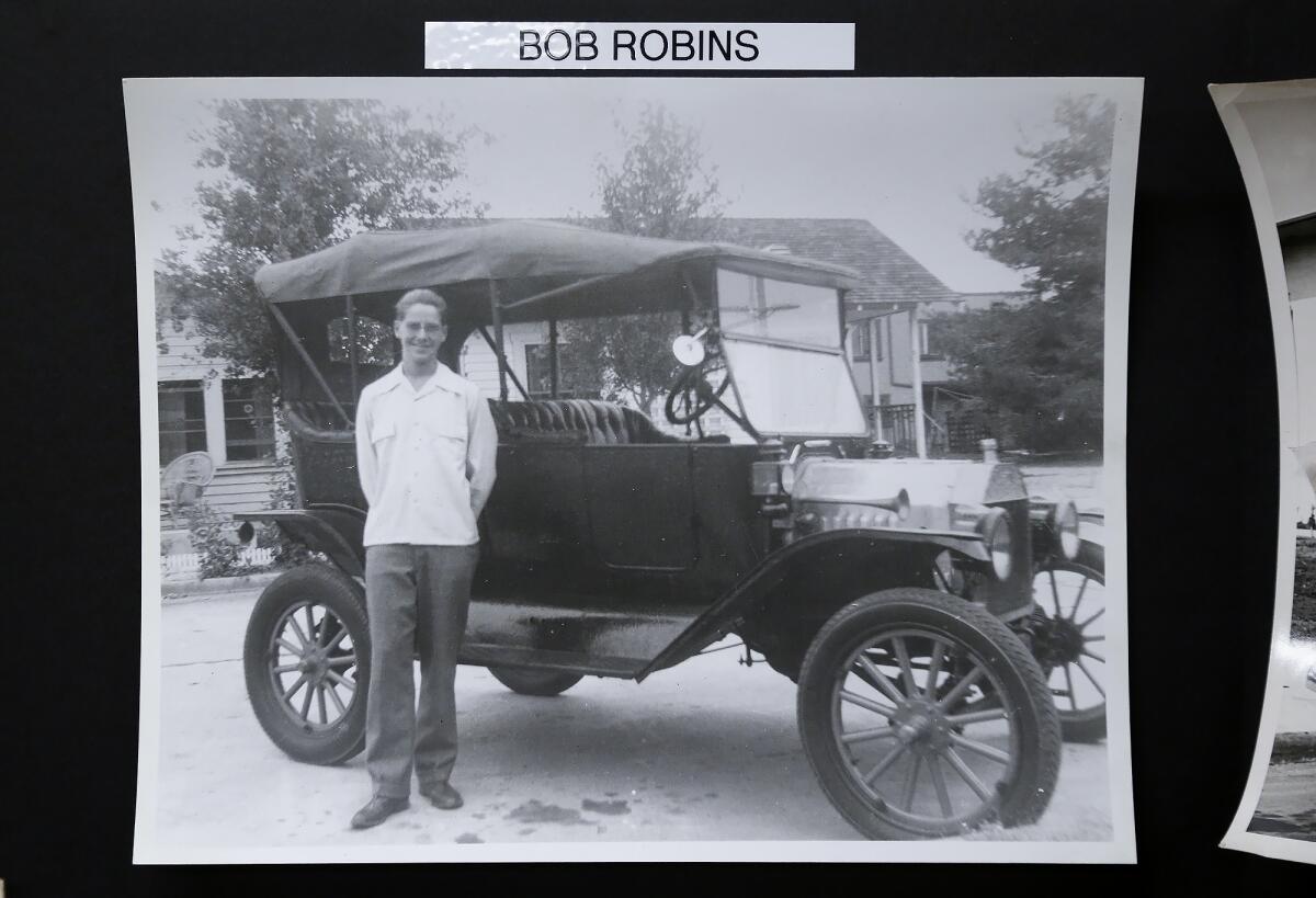 An undated photo shows Theodore "Bob" Robins Jr. standing next to a Model-T Ford in Newport Beach.