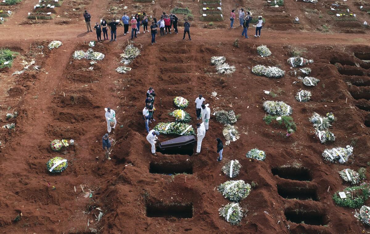 FILE - In this April 7, 2021, file photo, cemetery workers wearing protective gear lower the coffin of a person who died from complications related to COVID-19 into a gravesite at the Vila Formosa cemetery in Sao Paulo, Brazil. Nations around the world set new records Thursday, April 8, for COVID-19 deaths and new coronavirus infections, and the disease surged even in some countries that have kept the virus in check. Brazil became just the third country, after the U.S. and Peru, to report a 24-hour tally of COVID-19 deaths exceeding 4,000. (AP Photo/Andre Penner, File)