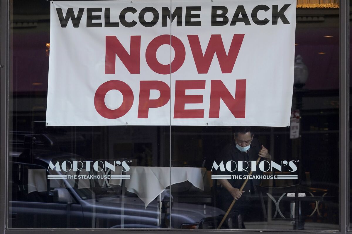 FILE - In this March 4, 2021, file photo, a sign reading "Welcome Back Now Open" is posted on the window of a Morton's Steakhouse restaurant as a man works inside during the coronavirus pandemic in San Francisco. California added 141,000 jobs in February as more than a quarter of a million people returned to the workforce. The California Employment Development Department said Friday, March 26, that the state's unemployment rate in February was 8.5%, down from 9% in January. (AP Photo/Jeff Chiu, File)