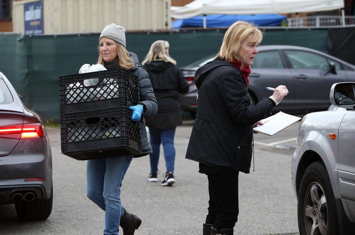 Anne Belyea, Lesli Henderson and Susan Thomas, from left, organize cars and get information from visitors receiving goods during drive-up distribution at the Laguna Food Pantry on Wednesday.