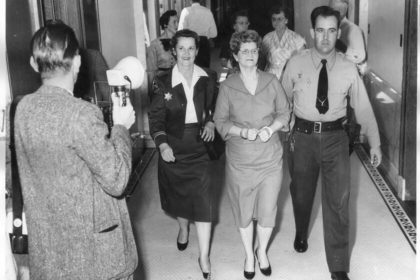 A March 17, 1959 file photo of Elizabeth Ann Duncan accompanied by Dep. Jeff Boyd, wearing a faint smile as she goes back to her cell to await the verdict to the jury.