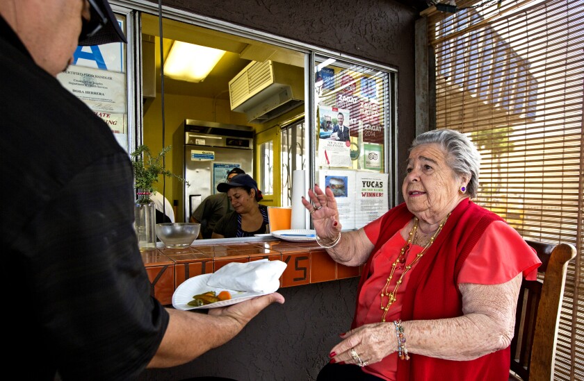 A woman takes orders at a taco restaurant.
