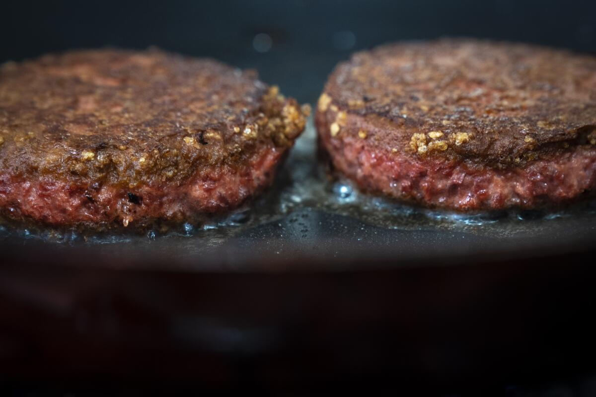 Two patties of Beyond Meat's meatless Beyond Burger cook in a skillet.