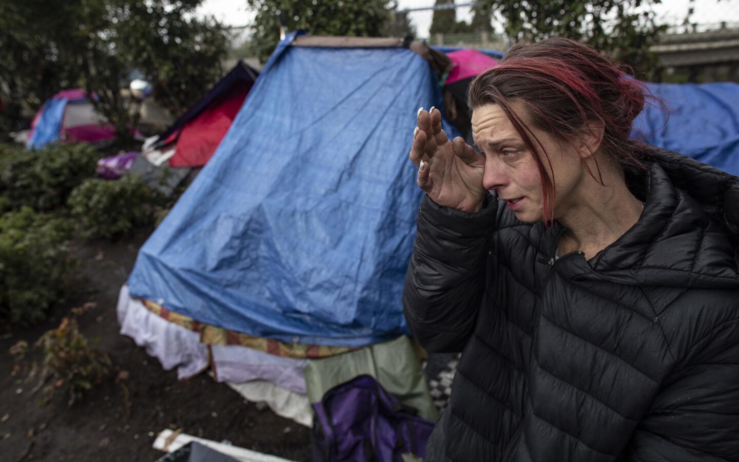 A woman who identified herself as Sky Smart, who has been homeless for 11 years, wipes a tear as she talks about her life at a homeless camp in Portland, Ore.