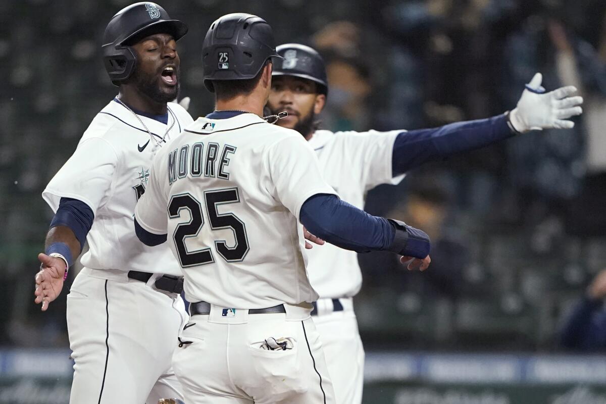 Seattle Mariners' Taylor Trammell, left, greets Dylan Moore (25) at the plate after they scored during the eighth inning of the team's baseball game against the San Francisco Giants, Thursday, April 1, 2021, in Seattle. (AP Photo/Ted S. Warren)