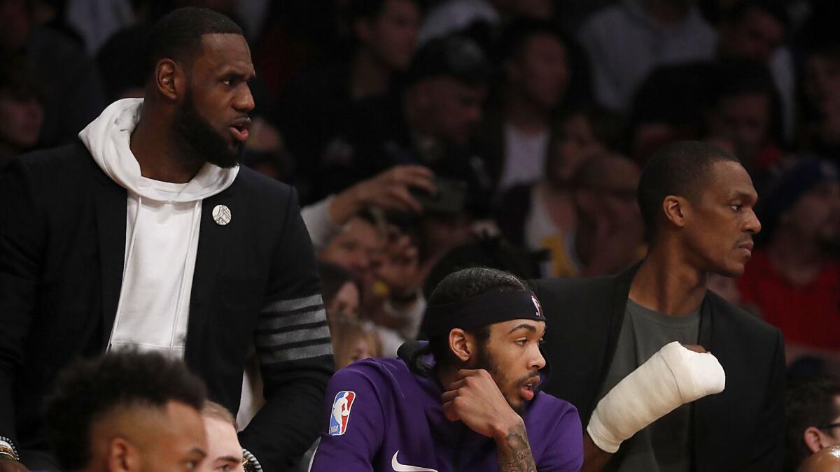 Lakers' LeBron James, left, Brandon Ingram (center) and Rajon Rondo (right) watch the game against the Clippers from the bench in the second quarter Friday night at Staples Center.