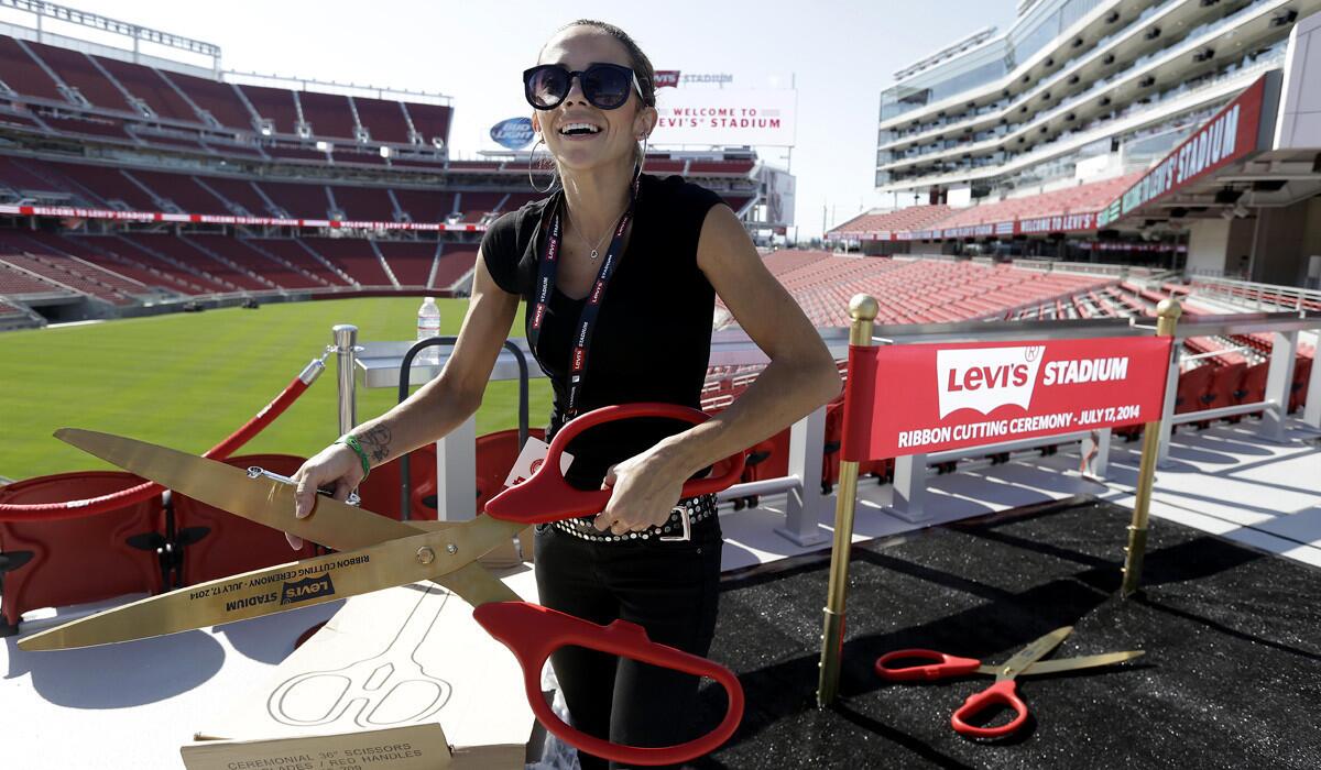 Mahelly Ferreira unpacks a large pair of scissors to be used in a photo booth before the ribbon-cutting ceremony and opening of Levi's Stadium on Thursday.