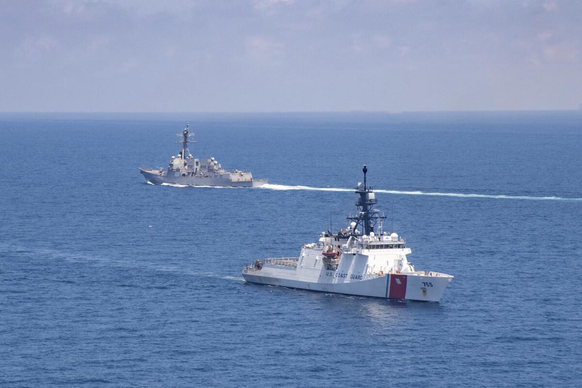 A U.S. Coast Guard vessel, front, passes a U.S.-guided missile destroyer in the Taiwan Strait.