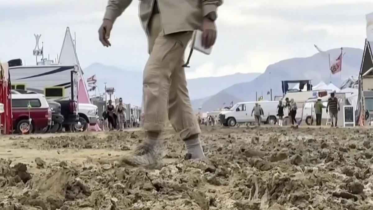 a man walks through mud at the Burning Man festival site 