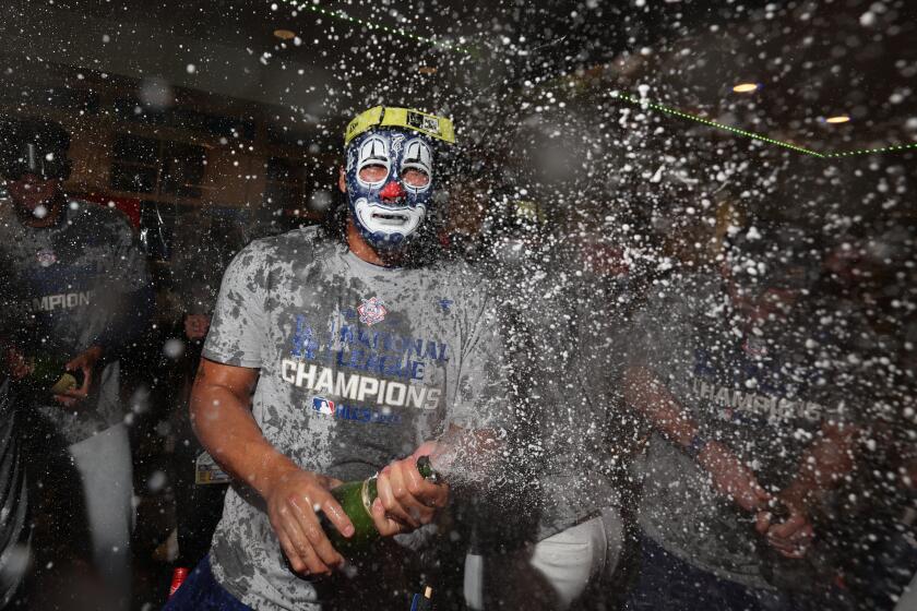 Brusdar Graterol wears a clown mask and sprays champagne while celebrating in the Dodgers locker room