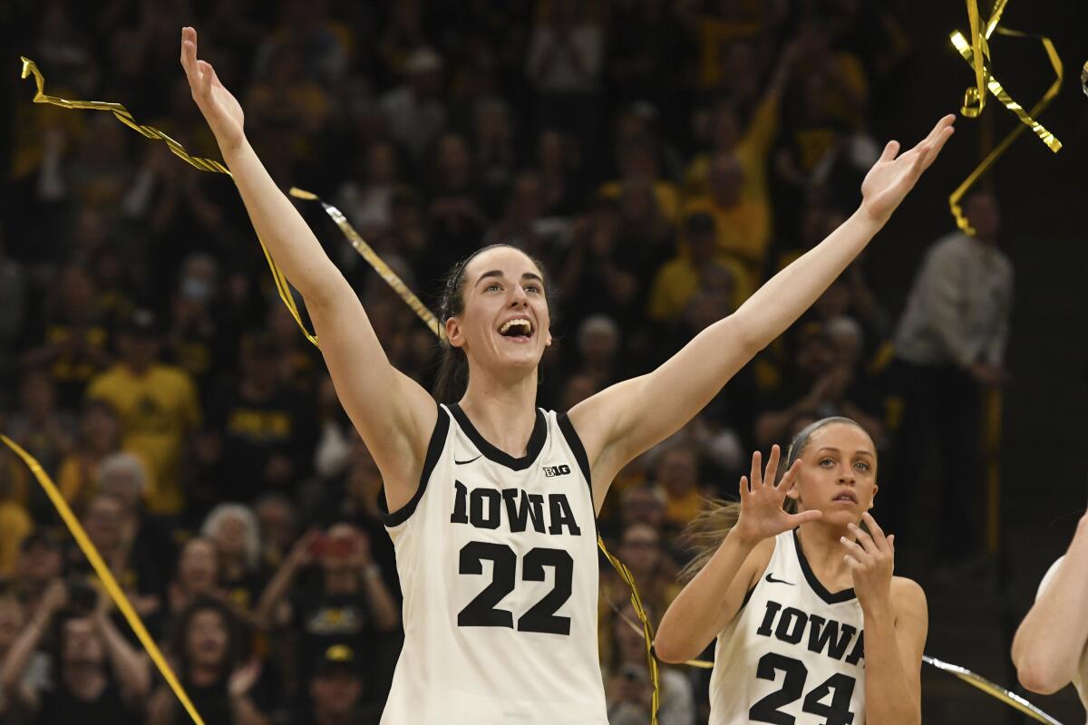 A female basketball player raises her arms in celebration