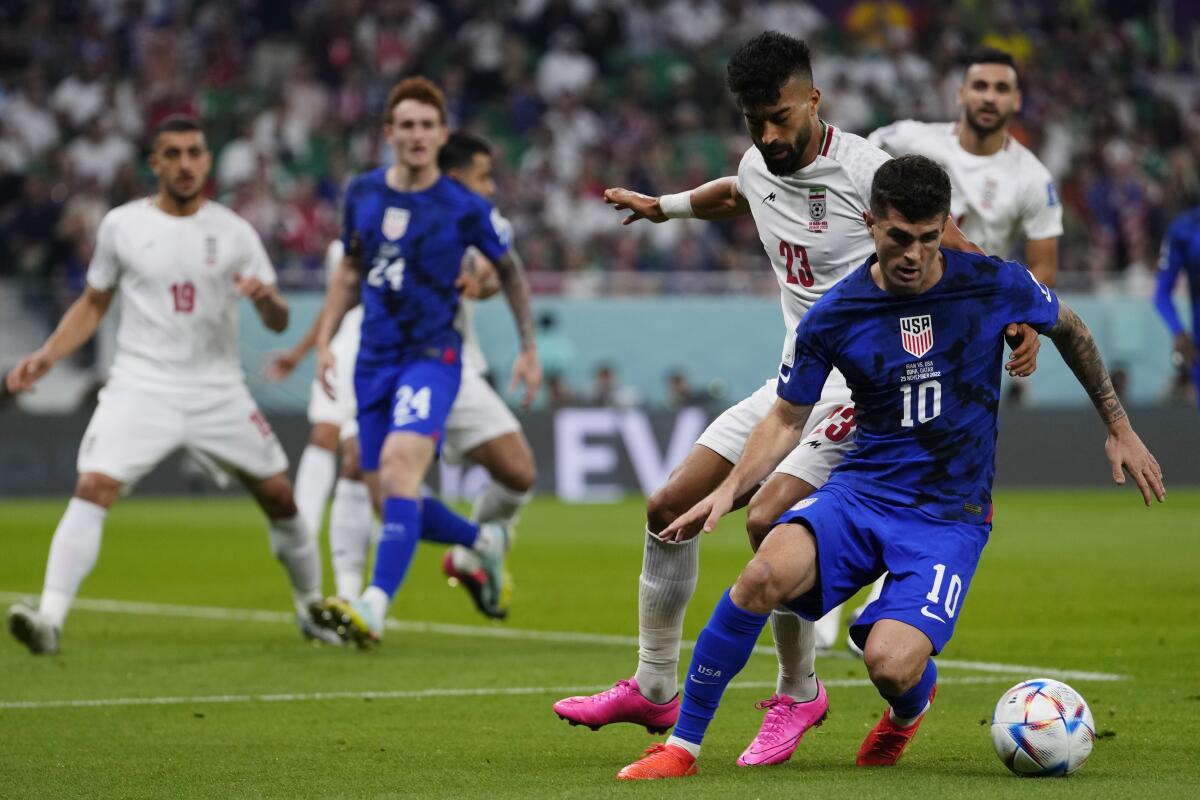 Iran's Ramin Rezaeian challenges U.S. forward Christian Pulisic, right, during the opening minutes.