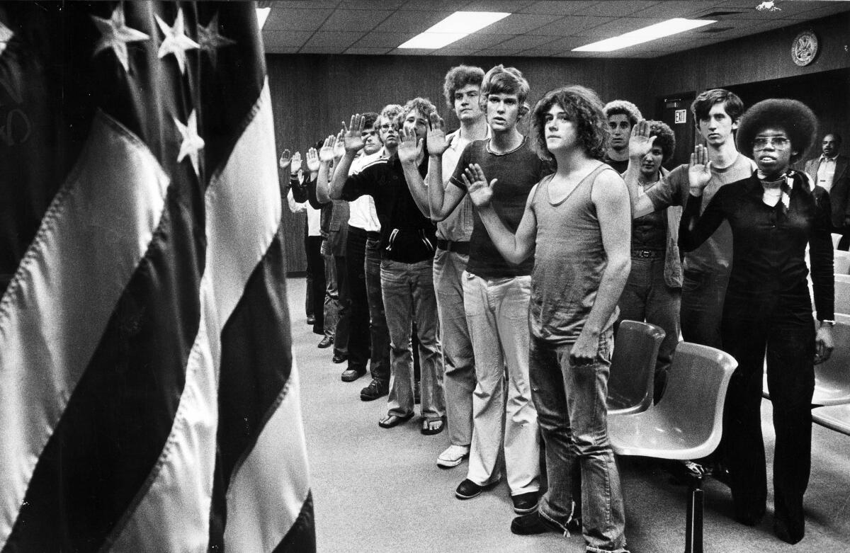 Oct. 12, 1977: 13 volunteers hold up their hands at an induction ceremony at the Armed Forces Building in Los Angeles
