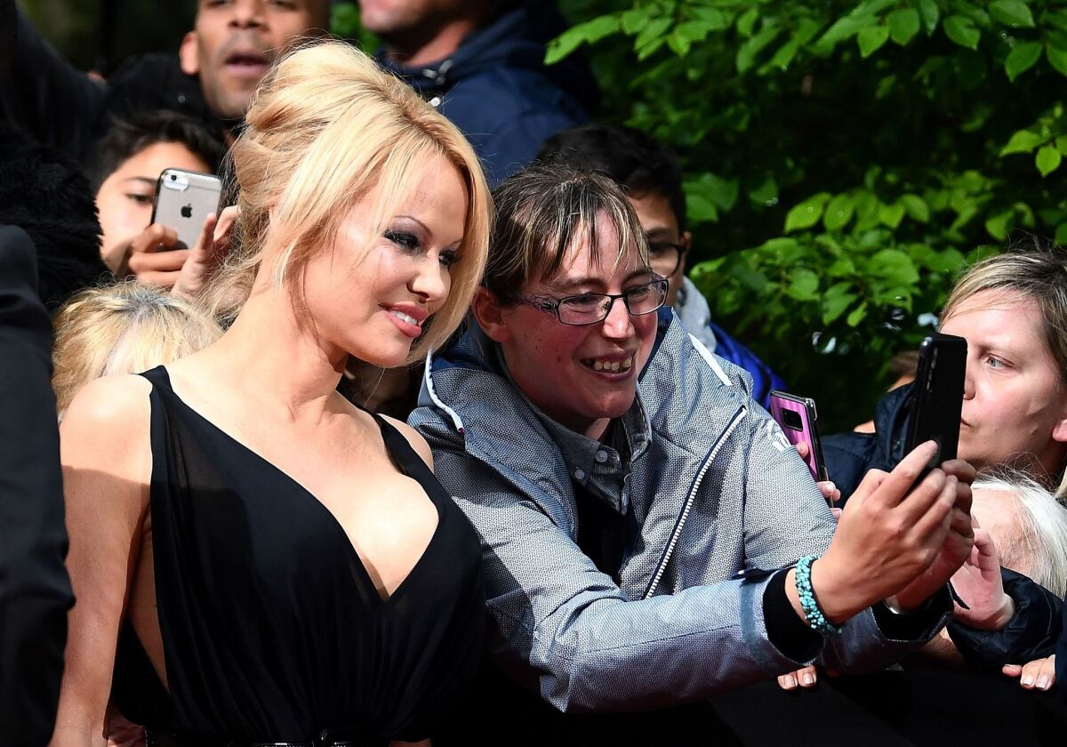 Pamela Anderson poses with a fan as she arrives to take part in a TV show last month in Paris.