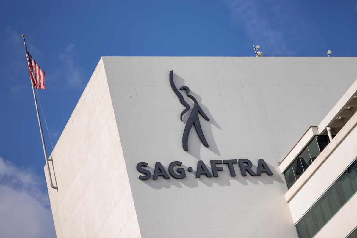 A white office building with the SAG-AFTRA logo on the side and an American flag on a flagpole