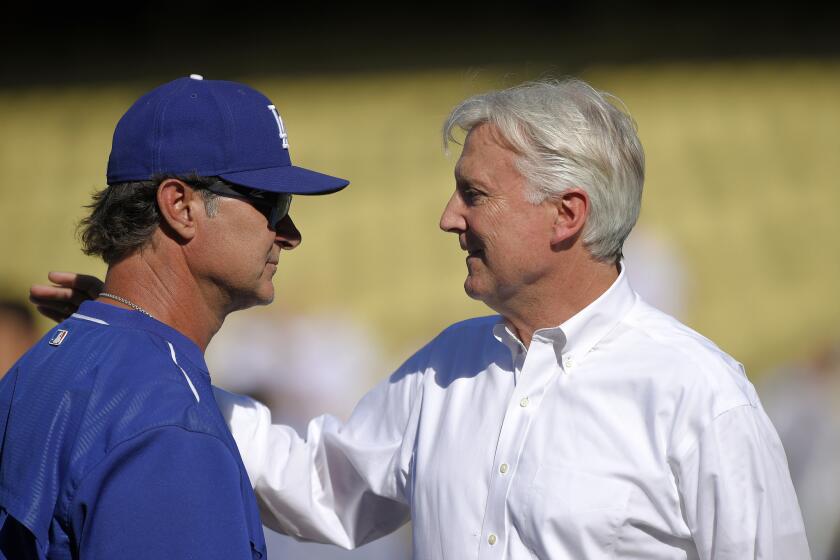 Dodgers Manager Don Mattingly talks with team co-owner Mark Walter, right, before a game against the Cincinnati Reds on Aug. 14.