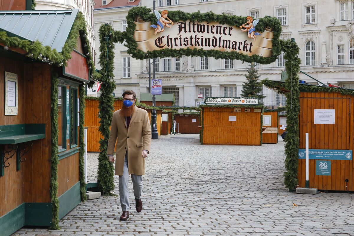 FILE - A person walks by a closed christmas market in Vienna, Austria, Tuesday, Nov. 30, 2021. As countries shut their doors to foreign tourists or reimpose restrictions because of the new omicron variant of the coronavirus, tourism that was just finding it's footing again could face another major pandemic slowdown amid the uncertainty about the new strain. (AP Photo/Lisa Leutner, File)