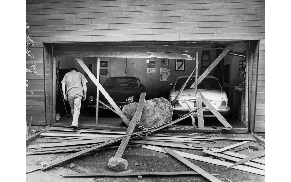 A man walks into his garage, where a boulder about 5 feet wide rests where the door, now splintered into boards, once was.