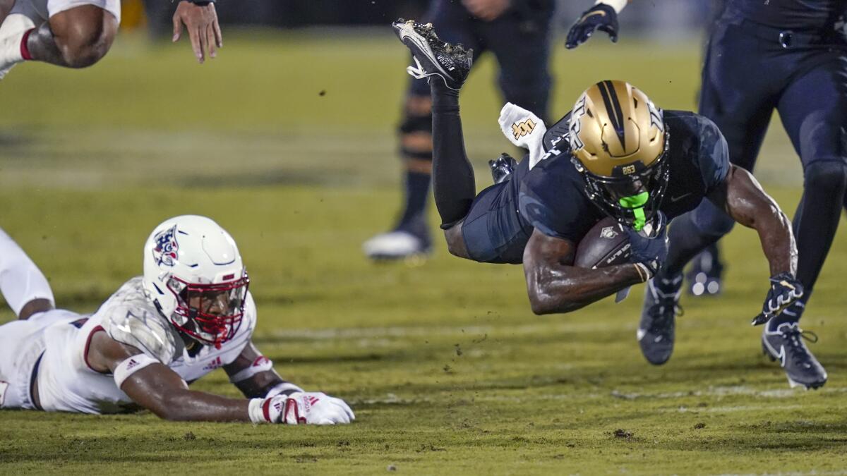 Louisville defensive back Kenderick Duncan, left, trips Central Florida running back Johnny Richardson during the first half of an NCAA college football game, Friday, Sept. 9, 2022, in Orlando, Fla. (AP Photo/John Raoux)