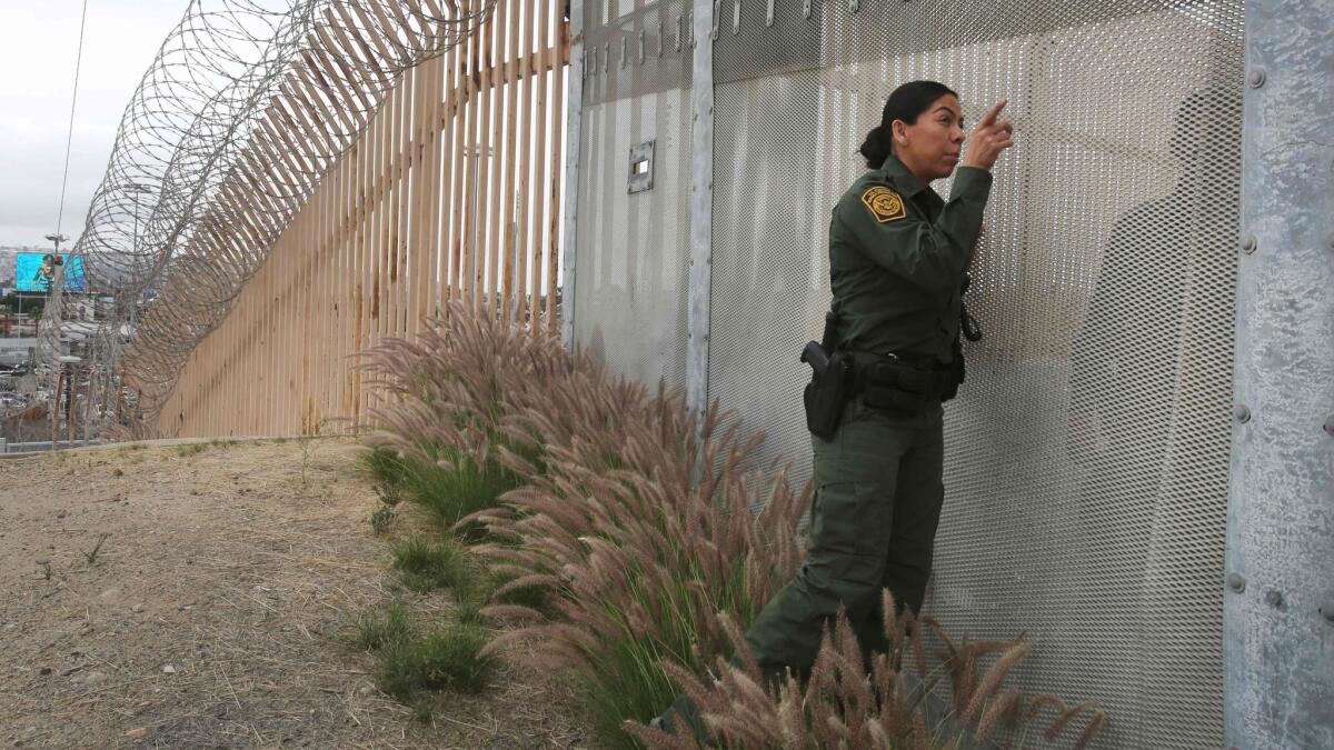 A Border Patrol agent talks with another agent through a fence at the U.S.-Mexico border in San Diego, California.