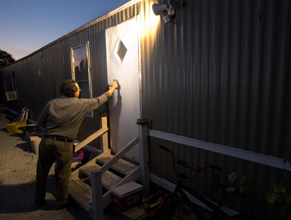 El agente del departamento de salud Antonio Tovar Aguilar golpea la puerta de la vivienda de un trabajador agrícola en Belle Glade, Florida, para interrogarlo sobre el uso de pesticidas.