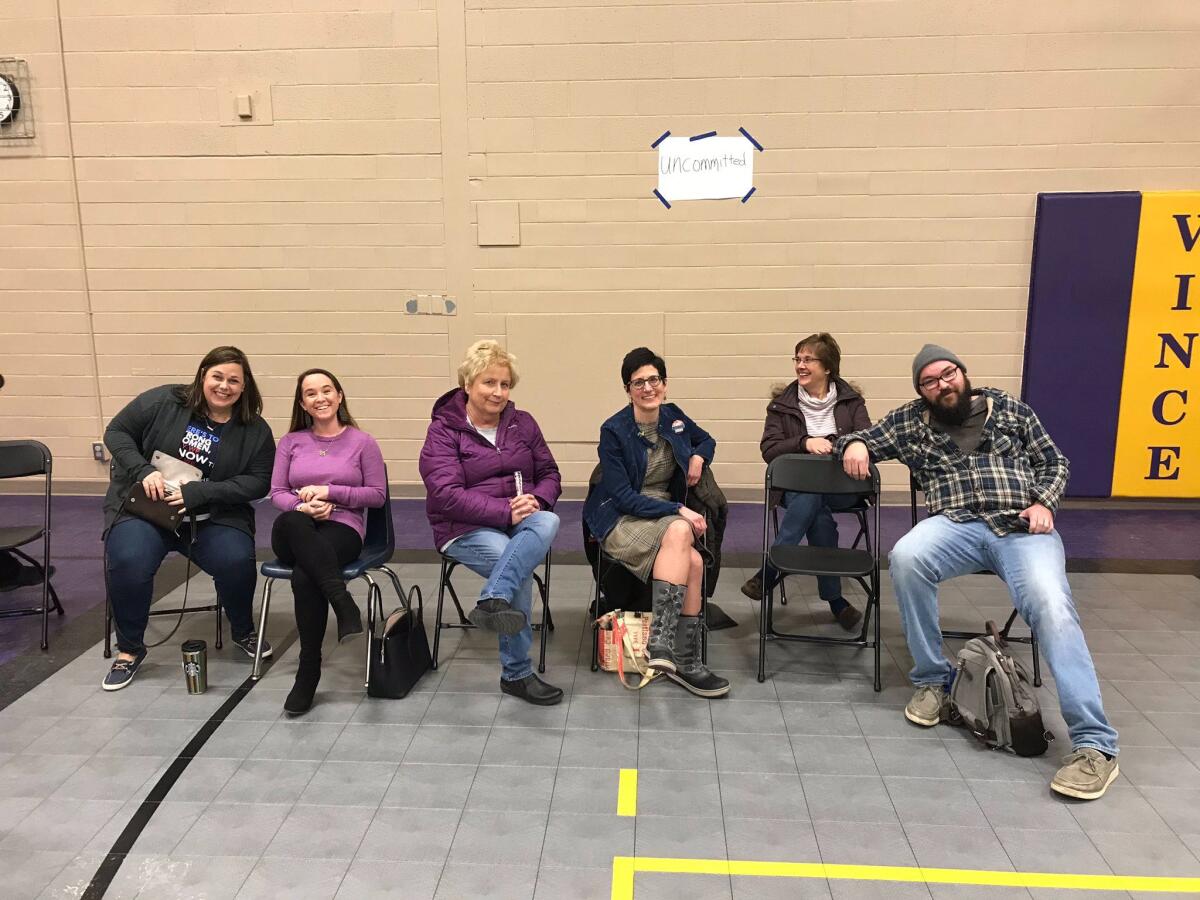 At a caucus precinct in Waukee, Iowa a small group of caucusgoers sit in in front of a sign that reads “uncommitted.”