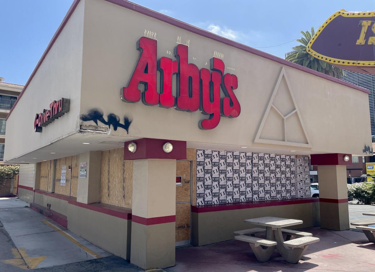 A photo of the exterior of Arby's Hollywood covered in plywood and wheat paste art.