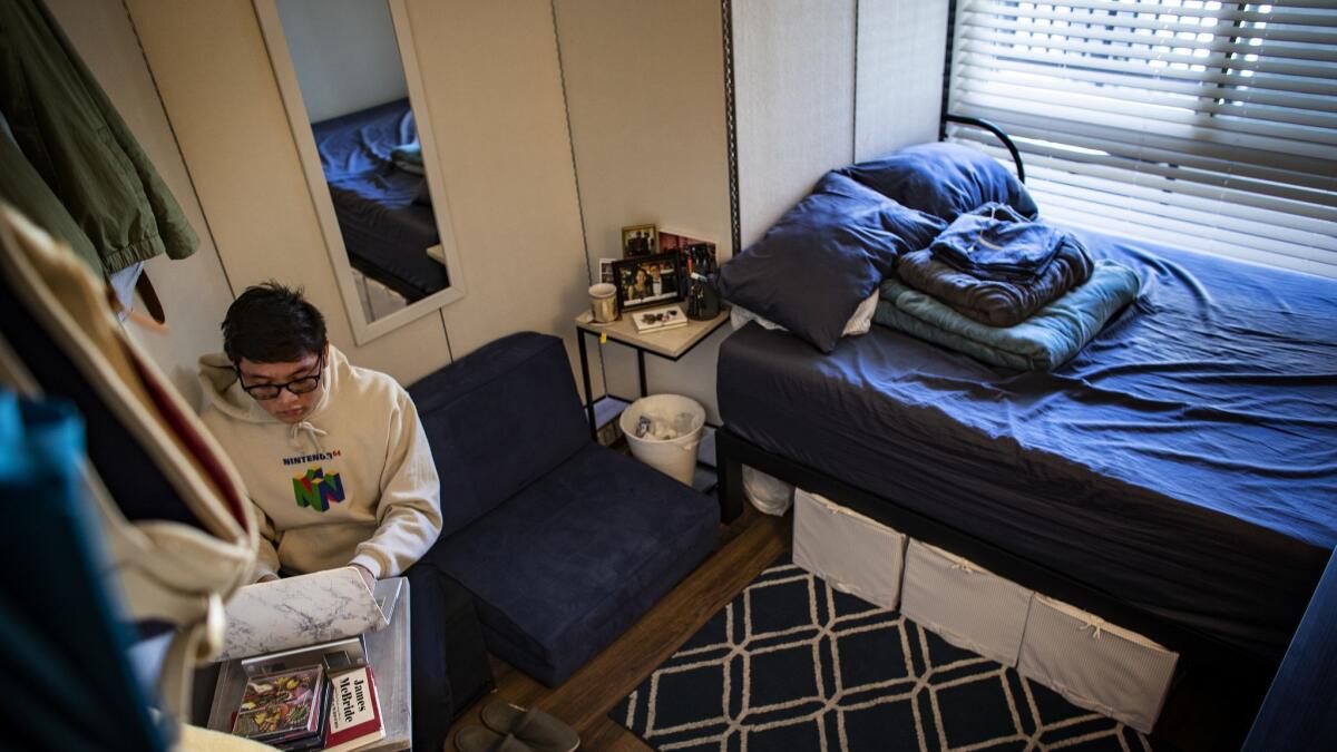 Christopher Cacho, 23, works on his computer in his bedroom, which is in the living room of a subdivided apartment in Glendale.