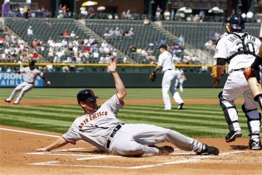 San Francisco Giants' Scott McClain, foregound, slides safely into home plate to score on a single by Travis Ishikawa as Colorado Rockies catcher Chris Iannetta, right, looks on during the first inning of a baseball game in Denver on Wednesday, Sept. 3, 2008. Giants' baserunner Aaron Rowand, back left, is caught in a rundown between second and third bases as Rockies starting pitcher Aaron Cook, back center, watches. Rowand was tagged out to end the inning. (AP Photo/David Zalubowski)