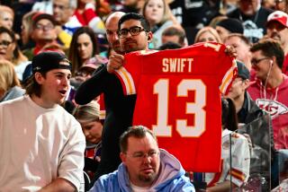 A fan holds up a Kansas City Chiefs jersey with Swift No. 13 on it.