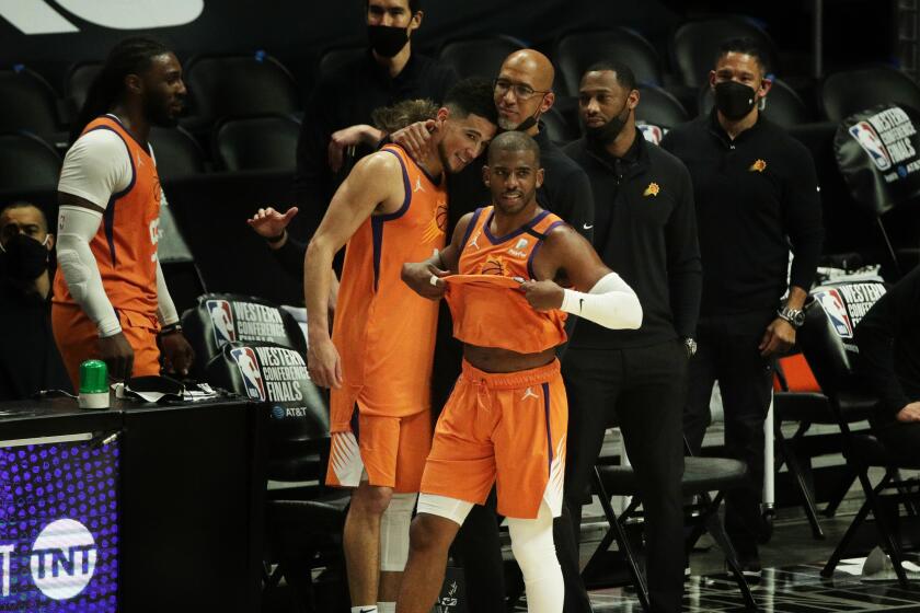 Suns Coach Monty Williams hugs Suns guard Devin Booker (1) as Suns guard Chris Paul watches the final seconds of Game 6.