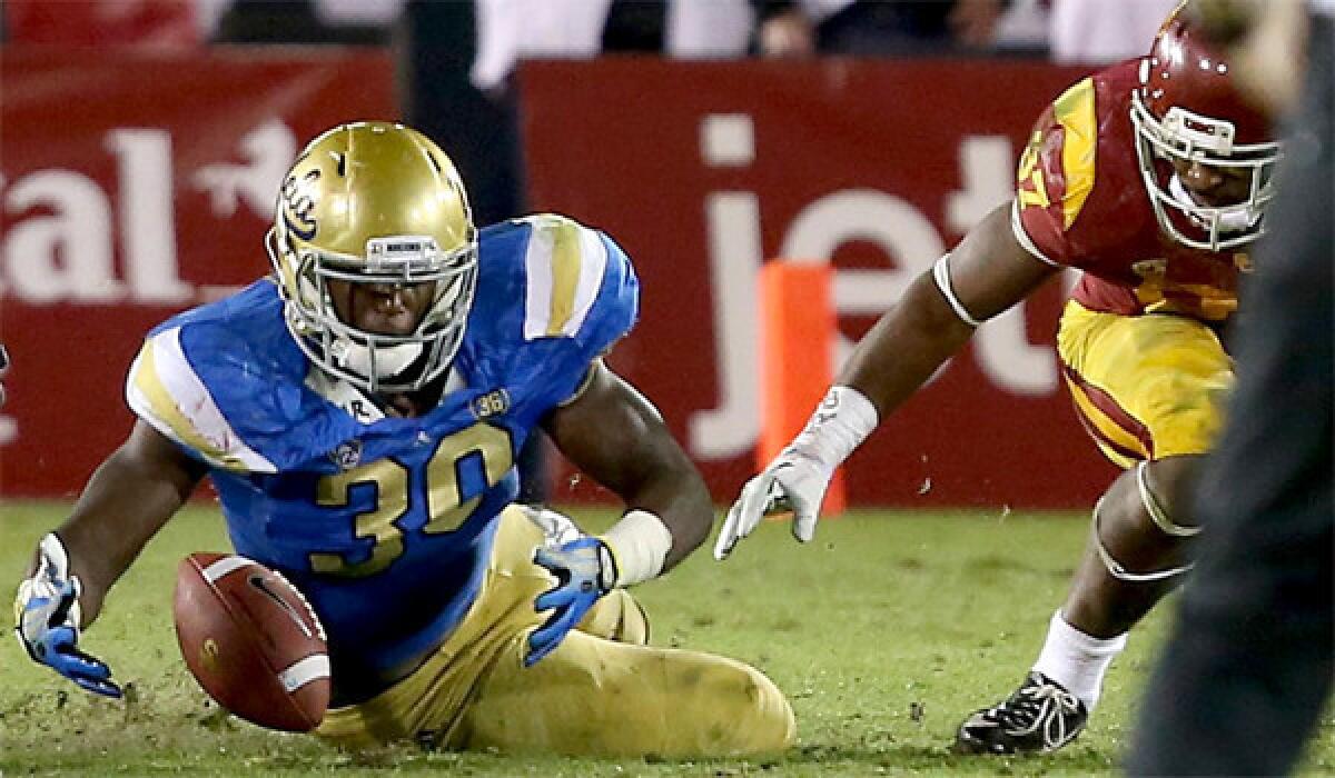 UCLA linebacker Myles Jack recovers a USC fumble during the Bruins' 35-14 win over the Trojans on Saturday at the Coliseum.