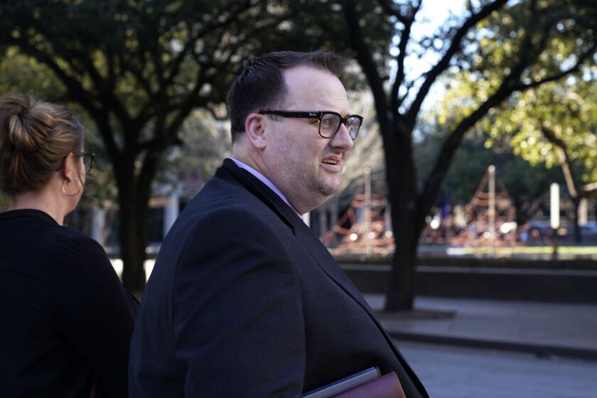 Former Los Angeles Angels employee Eric Kay, foreground waits to cross the street after exiting federal court Tuesday, Feb. 15, 2022, in Fort Worth, Texas, where he is on trial for federal drug distribution and conspiracy charges. Kay is accused of providing Tyler Skaggs the drugs that led to the pitcher's overdose death. The 27-year-old Skaggs was found dead in July 2019 in a suburban Dallas hotel room. He had choked to death on his vomit, and a toxic mix of alcohol, fentanyl and oxycodone was in his system. (AP Photo/LM Otero)